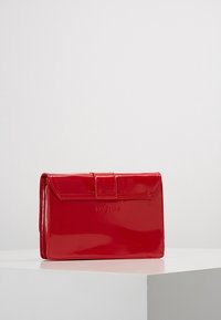 Czerwony portfel z lakierowanej skóry o prostokątnym kształcie, z klapką na złożenie i zapięciem na zatrzask. Na przedniej stronie znajduje się wytłoczone logo.