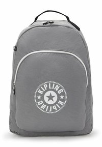 Sac à dos en tissu gris de forme arrondie, doté d'une poche frontale zippée blanche et d'un logo circulaire avec un motif d'étoile.