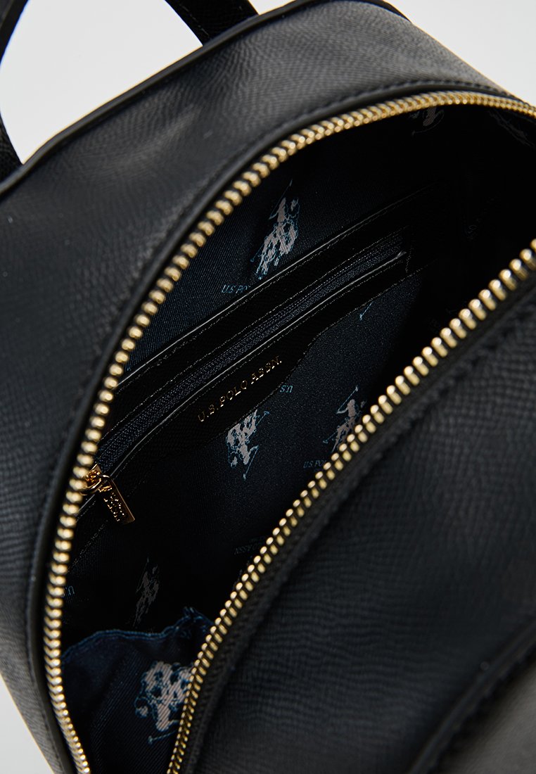Zaino in pelle nera con zip dorata. L'interno presenta un tessuto scuro con loghi blu chiaro ripetuti e compartimenti con zip aggiuntivi.