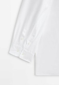 Camicia bianca a maniche lunghe caratterizzata da una texture liscia, colletto a punte, polsini con bottone e chiusura con due bottoni in madreperla.
