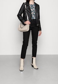 Černá kožená motorkářská bunda, květinový top, černé džíny s vysokým pasem, béžová kabelka přes rameno s řetízkem a krémové kotníkové boty s černými akcenty.