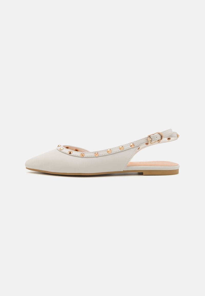 Chaussure slingback plate blanche à bout pointu avec des détails cloutés dorés et une petite boucle dorée sur un fond uni.
