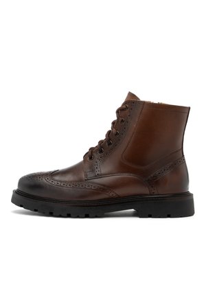 Brązowe skórzane botki na kostkę z detalami w stylu brogue, okrągłym noskiem, sznurowanym zapięciem i grubą czarną gumową podeszwą. Gładka faktura z kontrastowymi akcentami.