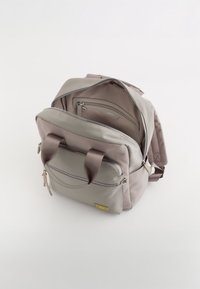 Mochila multifuncional gris con asas superiores dobles, bolsillo frontal con cremallera y múltiples compartimentos interiores. Textura suave y material duradero.