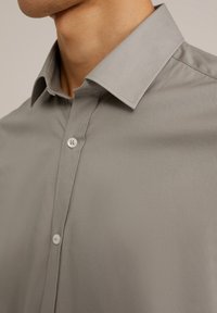 Chemise grise à boutonnières avec un col classique, texture lisse et éclat subtil, avec des boutons blancs visibles à l'avant.
