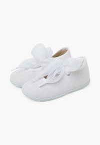 Zapatos de tela blancos con una superficie texturizada, punta redonda y lazos anchos de cordones en la parte frontal. Suelas de goma planas para agarre y flexibilidad.
