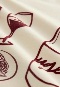 Tissu en coton avec un fond crème, comportant des illustrations en bordeaux d'un verre, d'une bouteille et d'un dessert, mettant en valeur une texture lisse et des détails.