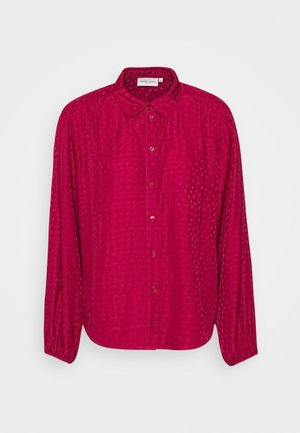Chemise rose foncé à manches longues, boutonnée, avec col et texture subtilement à motifs sur fond blanc.