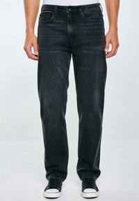 Jeans in denim nero con vestibilità a gamba dritta, dotati di cinque tasche, cuciture a contrasto e texture consumata. Abbinati a sneakers nere.