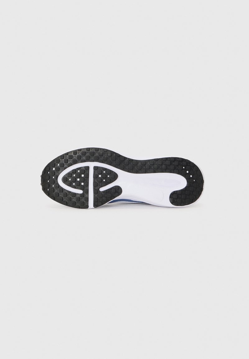 Suela de goma negra con agarre texturizado, entresuela blanca y acentos azules. Presenta una forma redondeada y un diseño suave y flexible para mayor comodidad.