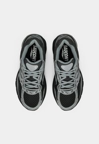 Sportovní boty v černé a šedé síťovině, s texturovaným svrškem, reflexními akcenty a šedými tkaničkami; výrazné logo značky na jazyku.