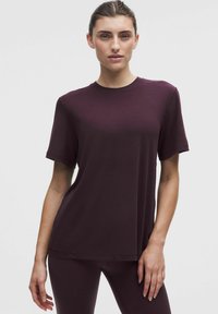 Burgundia lühikeste varrukatega t-särk ümmarguse kaelusega, pehmest kangast, lõdva istuvuse ja lihtsa disainiga ilma mustrite või aktsentideta.