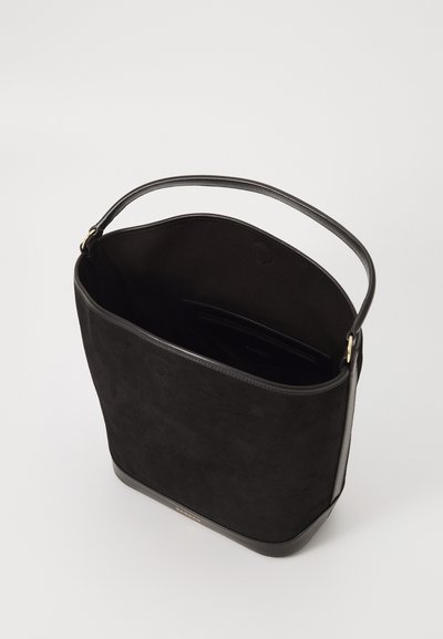 Svart mockaväsk med en slät läderbotten och ett enda handtag på toppen. Inuti finns organiseringsfickor. Minimalistisk design.