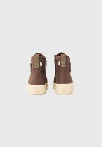 Botines de textil marrones con suela de goma beige, que presentan cremalleras en los laterales y tiradores de tela para facilitar el calzado.