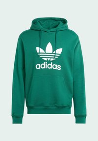 Zelená mikina s kapucňou vyrobená z veľmi jemnej textílie, s bielym logom adidas a grafikou troch listov. Obsahuje klokaní vrecko a stiahnuteľný šnúrku na kapucni.