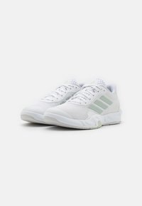 Scarpe da ginnastica bianche con tomaia in mesh, caratterizzate da accenti verde chiaro e tre strisce sul lato. Suola imbottita e design traspirante.