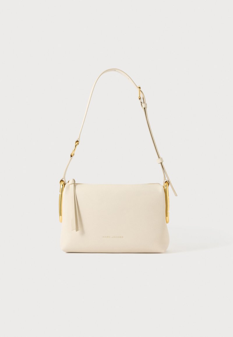 Sac à main rectangulaire couleur crème avec bandoulière réglable et détails métalliques dorés, avec un logo Marc Jacobs discret sur le devant.
