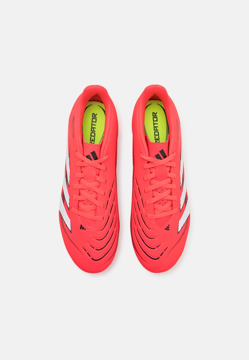 Botas de fútbol de color rojo brillante con parte superior texturizada, franjas blancas y acentos negros. Presenta punta redonda y diseño con cordones.