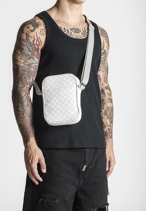 Borsa a tracolla a quadri bianchi con chiusura a zip e tracolla grigia, caratterizzata da una forma rettangolare piatta e una texture liscia.