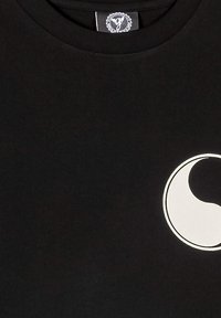 Camiseta de algodón negra con un gran logo de media luna blanca en el frente. Cuello redondo y mangas cortas. Textura suave y lisa.