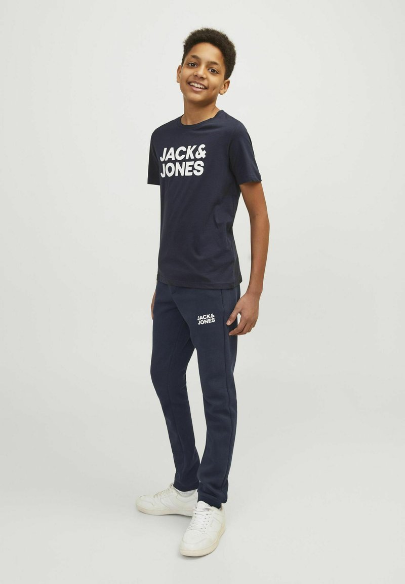 Marineblauw t-shirt en sweatpants met wit "JACK & JONES" logo. Katoenen materiaal, casual pasvorm, eenvoudig ontwerp, gecombineerd met witte sneakers.