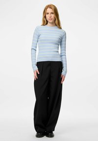 Gaiši zils, ribots, ar garām piedurknēm tops ar dzeltenām horizontālām svītrām, kombinēts ar melnām platām biksēm un melniem apaviem.