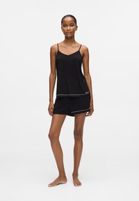 Sort camisole med tynde stropper, lagdelt design; matchende sorte shorts med hvide detaljer, blødt materiale, afslappet pasform.