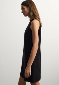 Vestito nero senza maniche con collo alto e decorazioni lungo il colletto, realizzato in tessuto liscio, caratterizzato da una linea dritta e senza motivi.