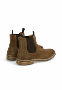 Bottines en daim marron avec des panneaux latéraux élastiques et des languettes de tirage. Présentent un bout arrondi et une semelle contrastante de couleur marron clair.