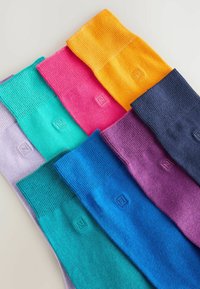 Barvne žabe do kolen v različnih odtenkih: vijolična, teal, roza, oranžna in temnomodra. Imajo rebrasto teksturo in prišito logo na vsaki.