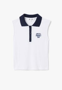 Hvid ærmeløs polo skjorte med en marinefarvet krave, har tre knapper og broderet tekst "COMPLETELY PERFECT 1985" i marineblå.