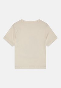 Camiseta de manga corta crema en una suave mezcla de algodón. Presenta un cuello redondo y un dobladillo recto. Textura lisa sin patrones o acentos visibles.
