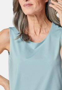 Top senza maniche blu chiaro con una texture liscia e scollatura rotonda, che mette in risalto dettagli di design semplici e una vestibilità rilassata.