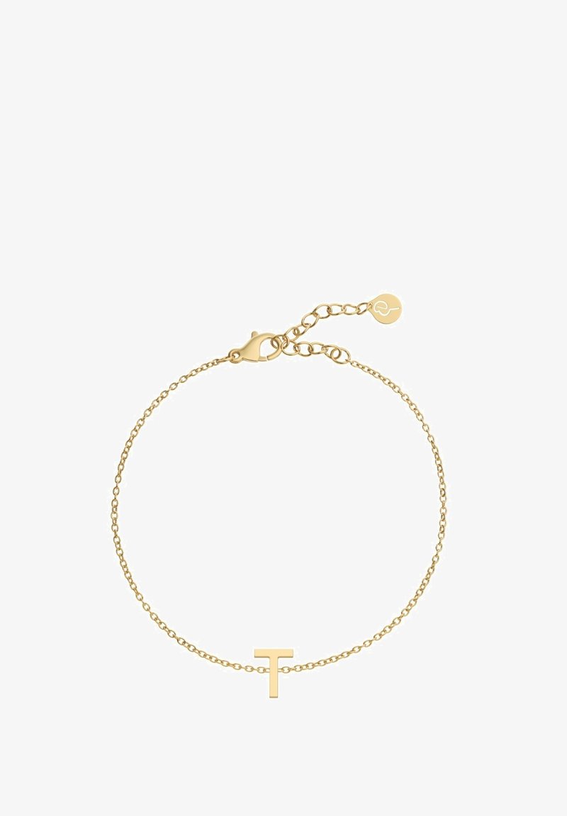 Zelta krāsas aproce ar smalku ķēdīti, kas rotāta ar minimālistisku 'T' piekariņu. Aprocessing ar asti un regulējamu garumu, kā arī neliela akcenta birka.