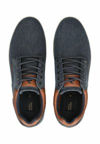 Modré denimové tenisky s hnědými koženými akcenty, kulatou špicí a bílou gumovou podrážkou; obsahují šest dírek na tkaničky a textilní povrch.