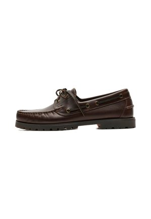 Chaussure bateau en cuir marron foncé avec détail de lacet, couture moc toe et semelle épaisse en caoutchouc sur fond blanc.