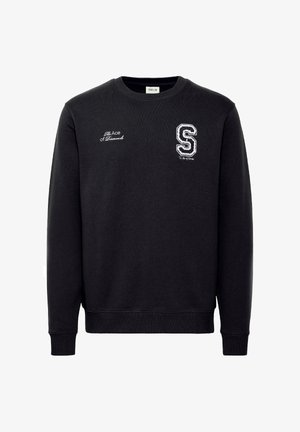 Fekete pulcsival, kerek nyakkal, hosszú ujjakkal, amelyen hímzett felirat található: "A Pikk Ász", valamint egy fehér "S" logó a mellrészen.