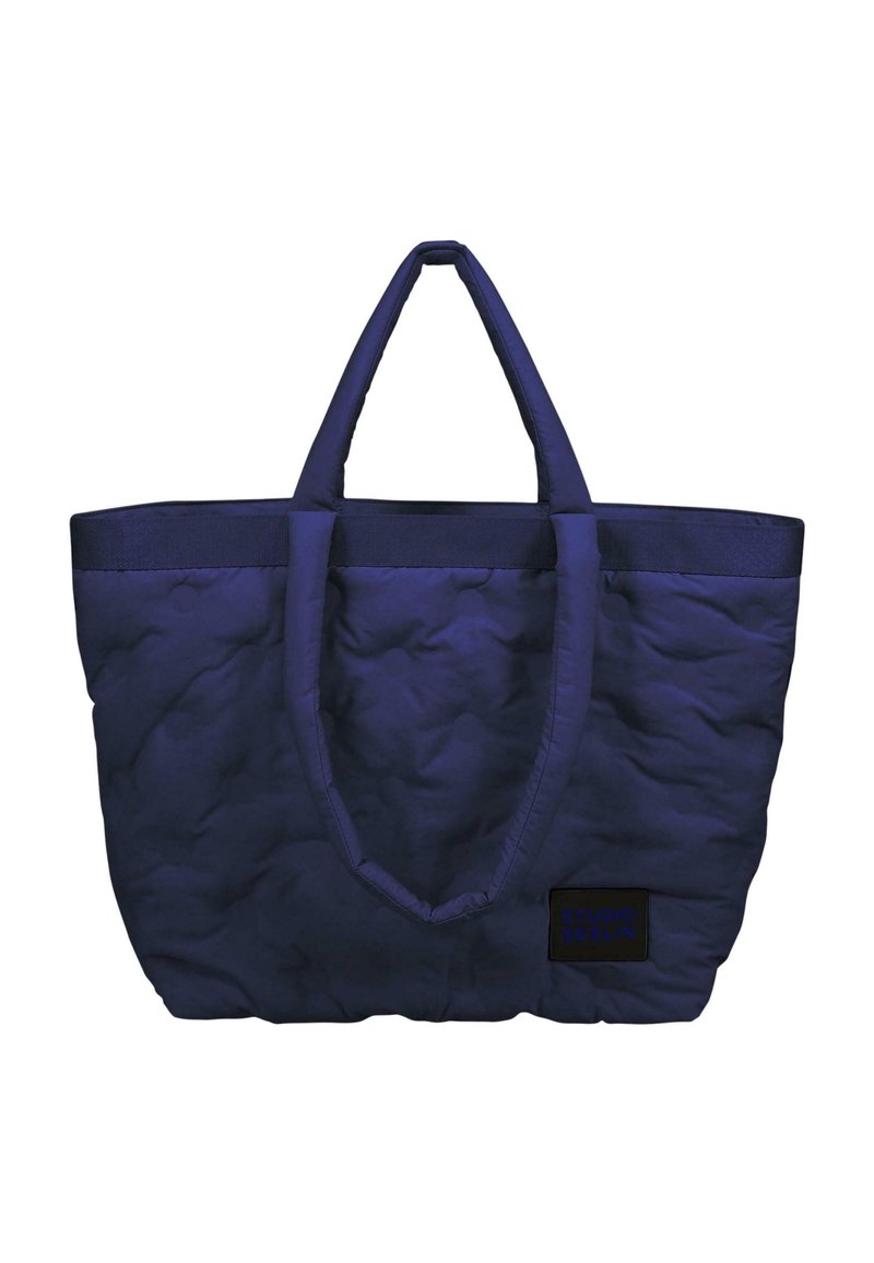 Borsa tote trapuntata blu navy con due manici in tessuto e base rettangolare. Presenta un piccolo etichetta nera con il testo "STUDIO BERLIN".