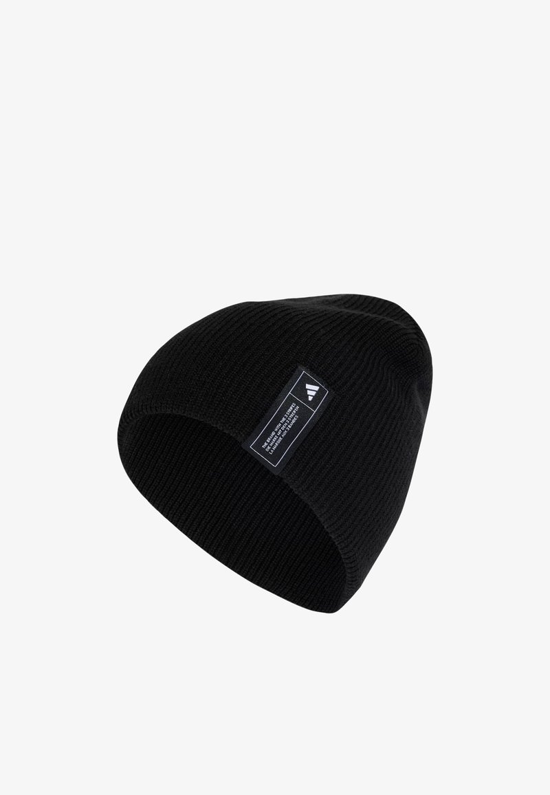 Zwarte gebreide beanie met een omgeslagen zoom, voorzien van een rechthoekig wit label met zwarte tekst en geometrische ontwerpaccenten. Gladde textuur.