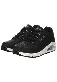Black athletic shoes with a leopard print texture, featuring a cushioned sole, white accents, and black laces. Brand logo is visible.