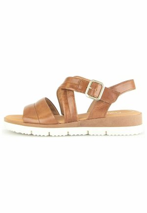 Sandales en cuir marron avec une large sangle pour les orteils, design entrecroisé et sangle de cheville réglable. La semelle est blanche et texturée pour une meilleure adhérence.