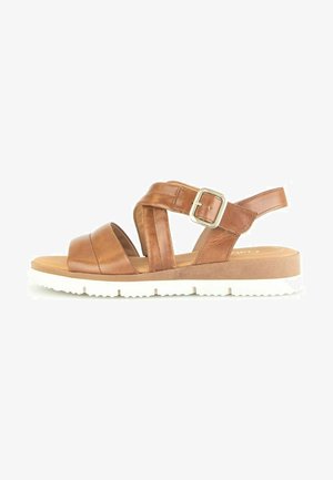 Sandali in pelle marrone con una larga fascetta per le dita, design incrociato e fascetta regolabile alla caviglia. La suola è bianca e strutturata per garantire aderenza.
