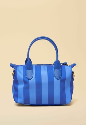 Niebieska torebka z pionowymi paskami, dwoma zaokrąglonymi uchwytami i zamkiem błyskawicznym na beżowym tle.