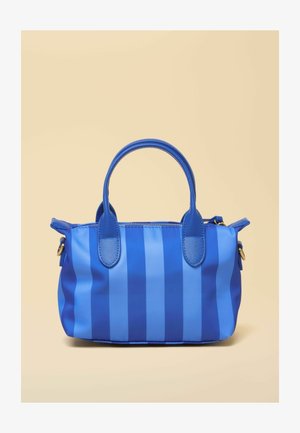 Niebieska torebka z pionowymi paskami, dwoma zaokrąglonymi uchwytami i zamkiem błyskawicznym na beżowym tle.