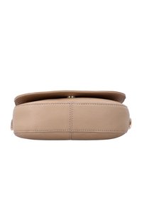 Beige læder crossbody taske vist fra bunden med synlige syninger og en lille metal lås på øverste kant.