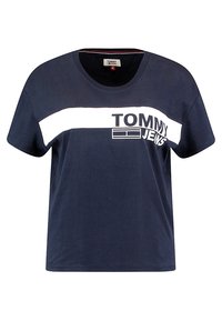 Mörkblå bomullströja med en vit horisontell remsa över bröstet med texten "TOMMY JEANS". Kort ärm och rund halsdesign.