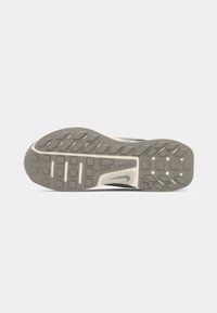 Grijze sneakerzool met een gestructureerd rubberpatroon, voorzien van een witte tussenzool en "NIKE TRAIL" branding, ontworpen voor grip en duurzaamheid.