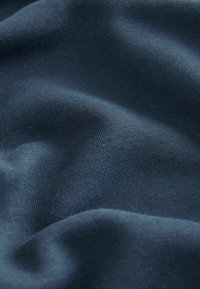 Țesătură de un albastru închis cu o suprafață netedă și texturată, având un model de tricot fin și delicate cute. Material moale și flexibil.