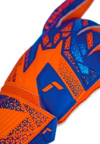 Guante de portero con un diseño vibrante en naranja y azul, superficie texturizada, patrones hexagonales y un detalle de logo distintivo.