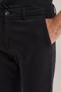 Černé bavlněné kalhoty s hladkou texturou, standardním zapínáním na knoflík a bočními kapsami. Design je úzký střih s minimálním šitím.